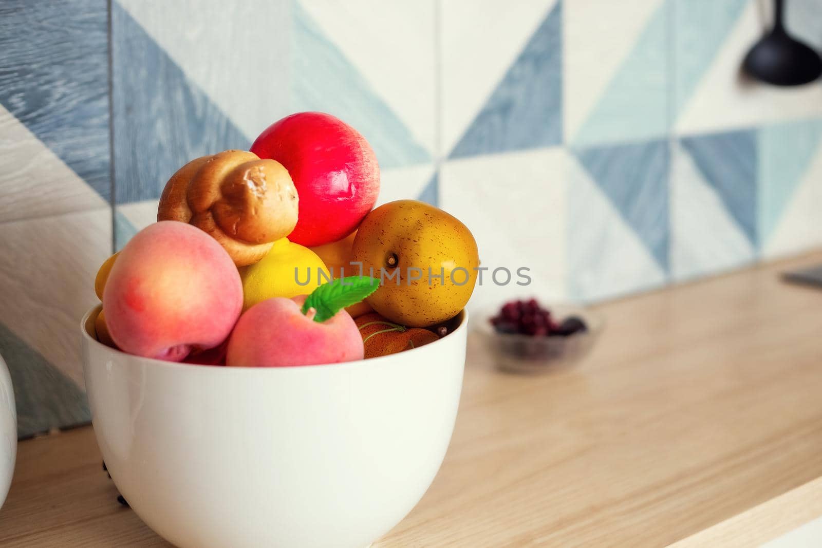 A large bowl of fruits and vegetables stands on the kitchen table, the background goes into blur, selective focus