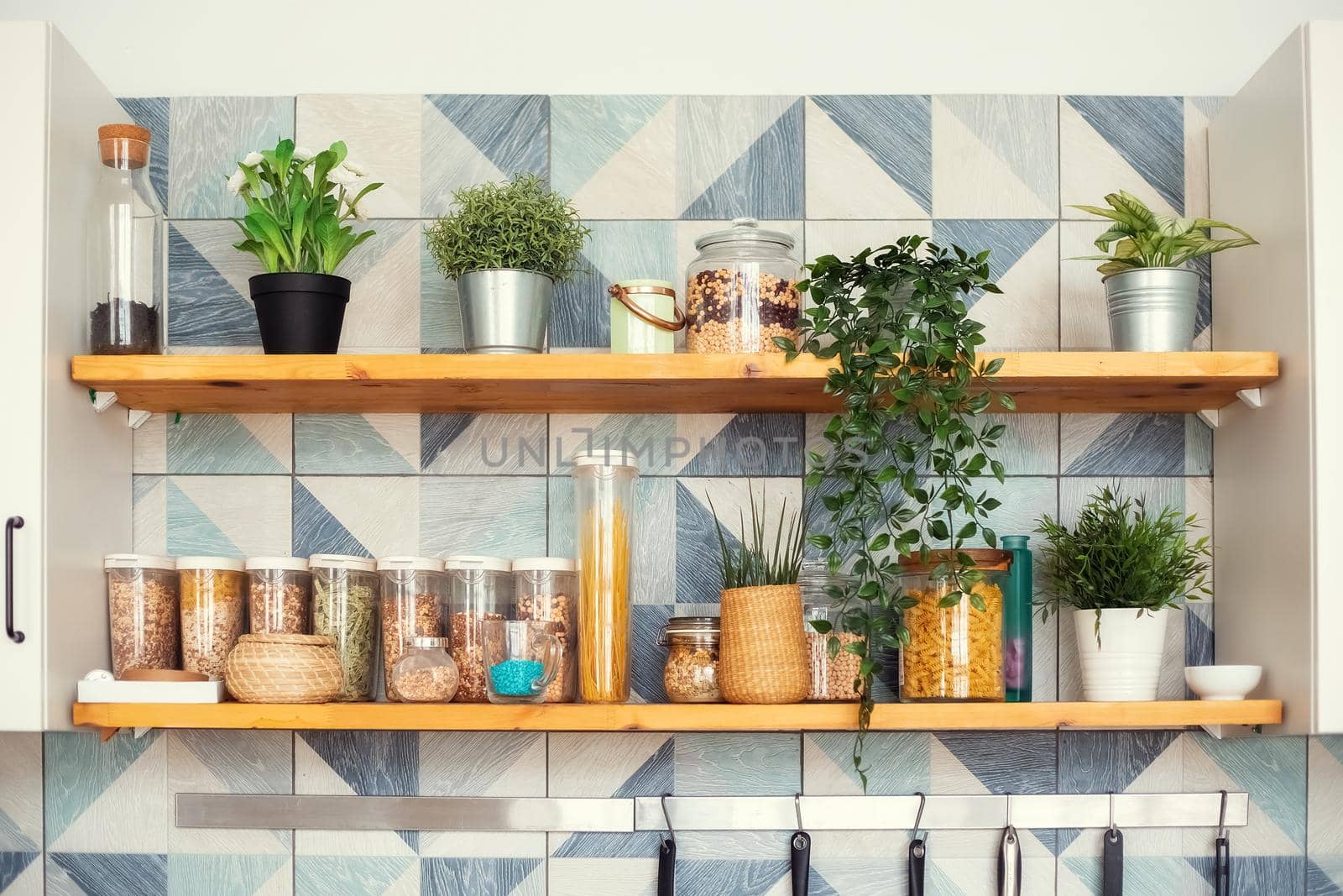 A variety of pasta in containers-cans with bulk products stand on shelves in two tiers in a bright Scandinavian-style kitchen, horizontal photo