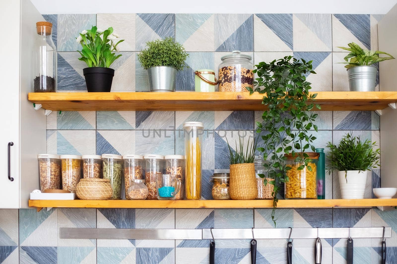 A variety of pasta in containers-cans with bulk products stand on shelves in two tiers in a bright Scandinavian-style kitchen, horizontal photo
