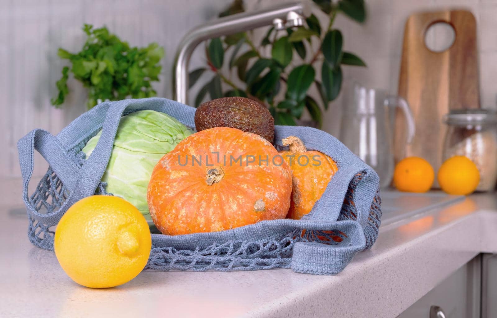 An eco-friendly shopping bag with vegetables lies on the work surface in the eco-friendly kitchen. Environmental protection concept, zero waste, recyclable. Selective focus.