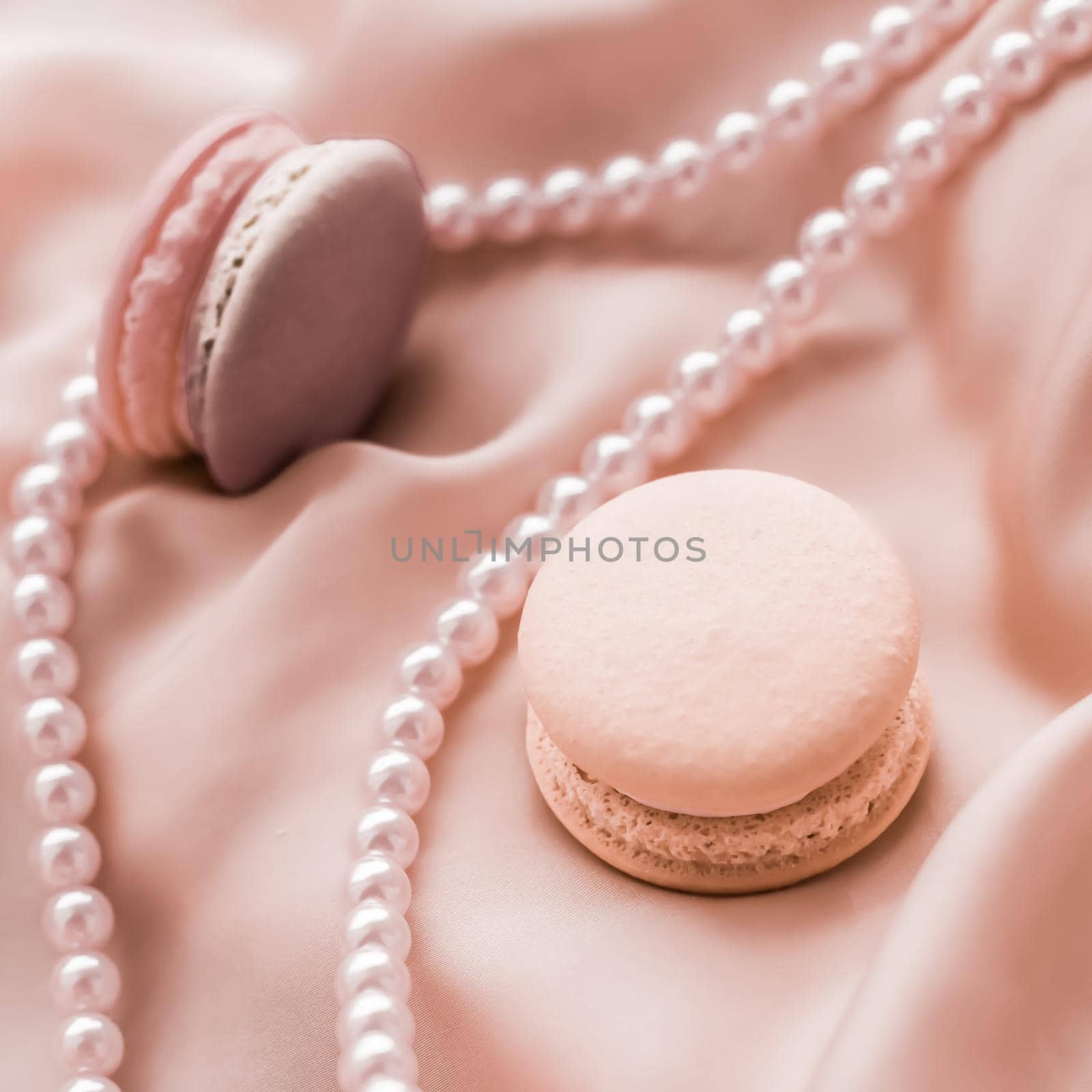 Sweet macaroons and pearls jewellery on silk background, parisian chic jewelry, French dessert food and cake macaron for luxury confectionery brand, holiday gift by Anneleven