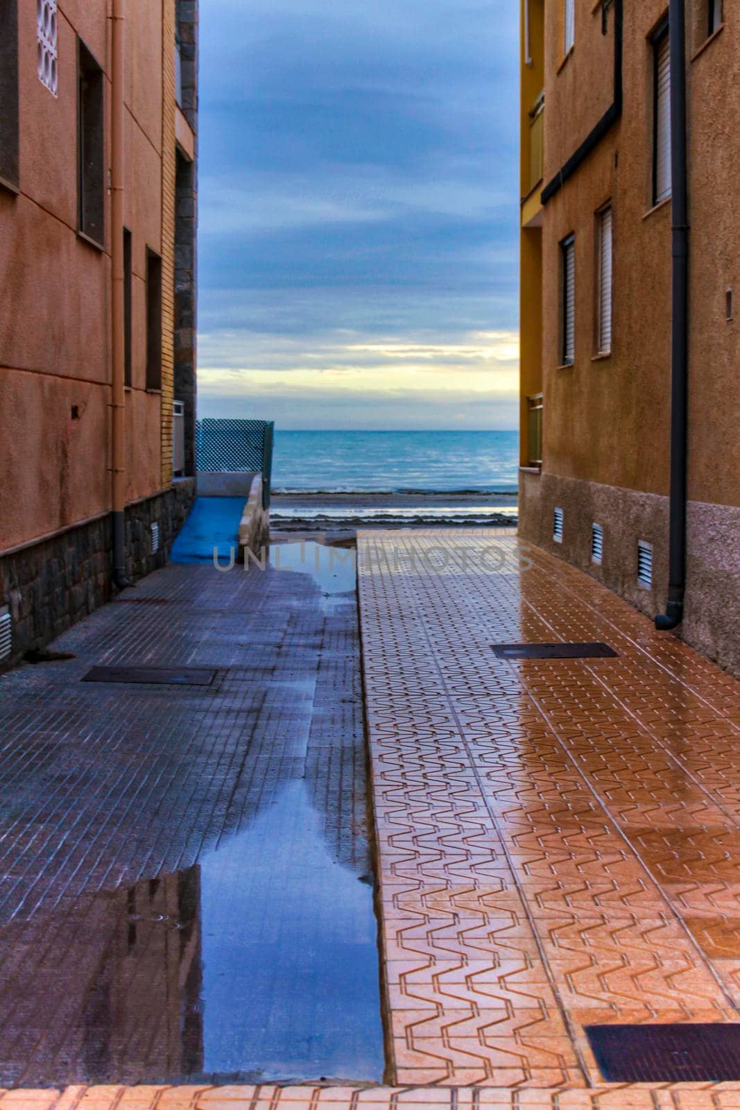 Lonely Little street between buildings facing the sea after a rainy day