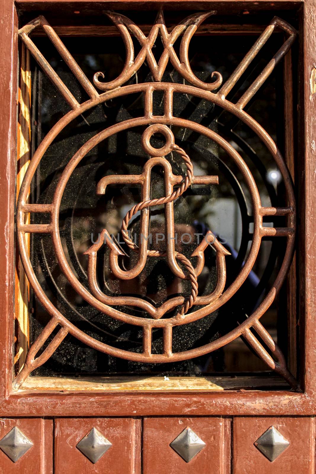Brown wooden door with anchor detail in wrought iron door in Alicante, Spain