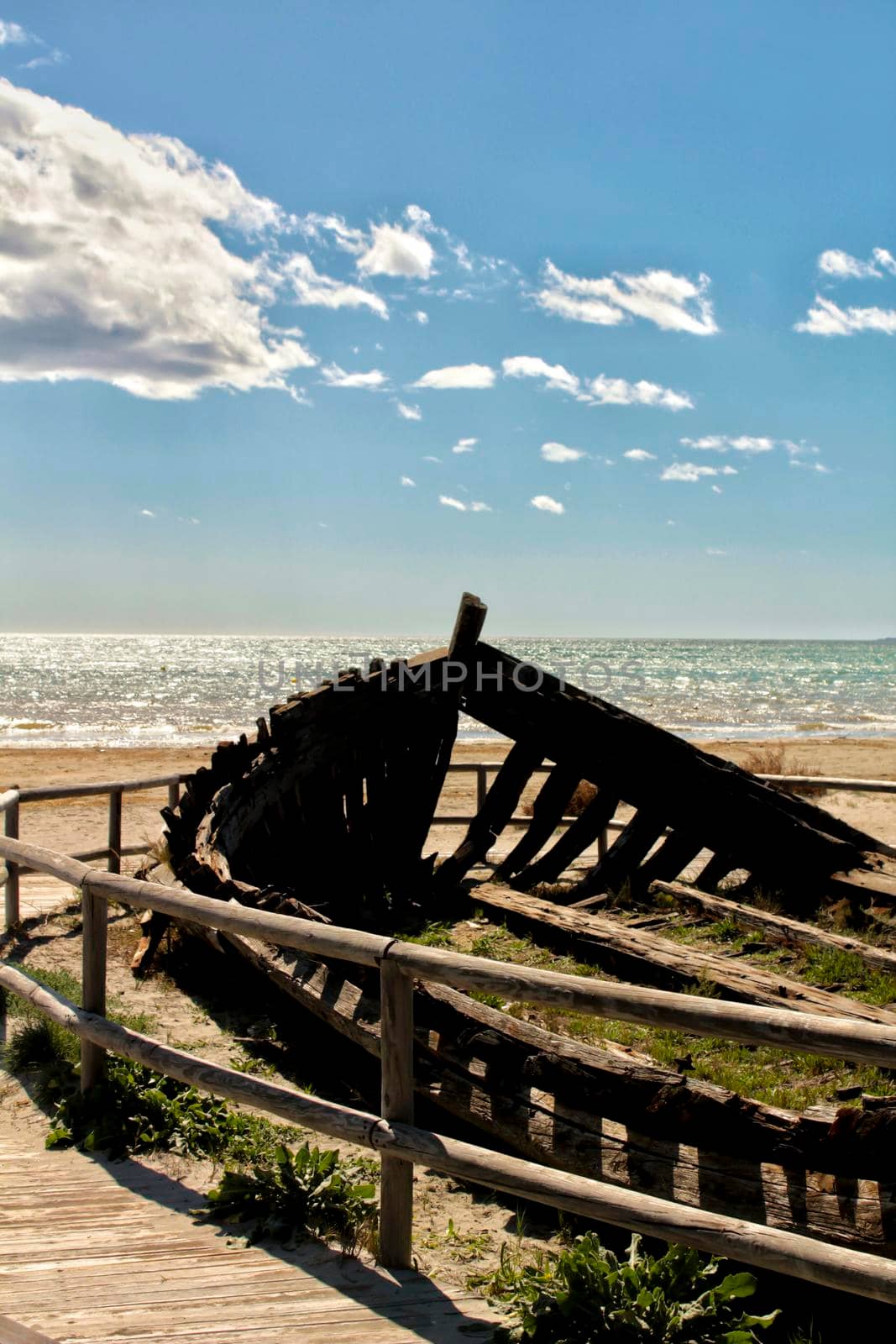 Old abandoned boat on the beach in Santa Pola. Salinas in the background under blue sky