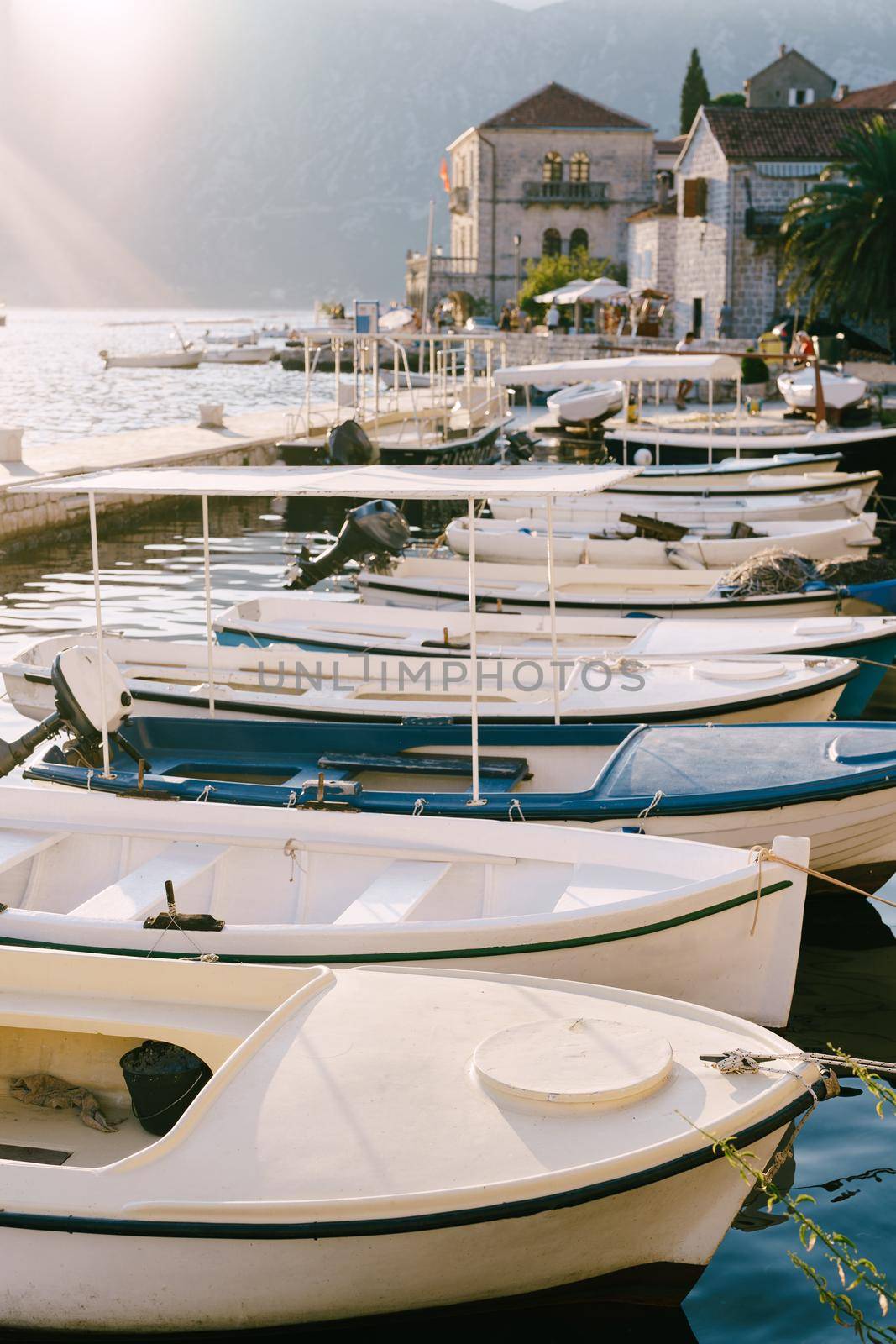 Fishing boats at the pier with houses in the background on a sunny day in Perast, Montenegro. High quality photo