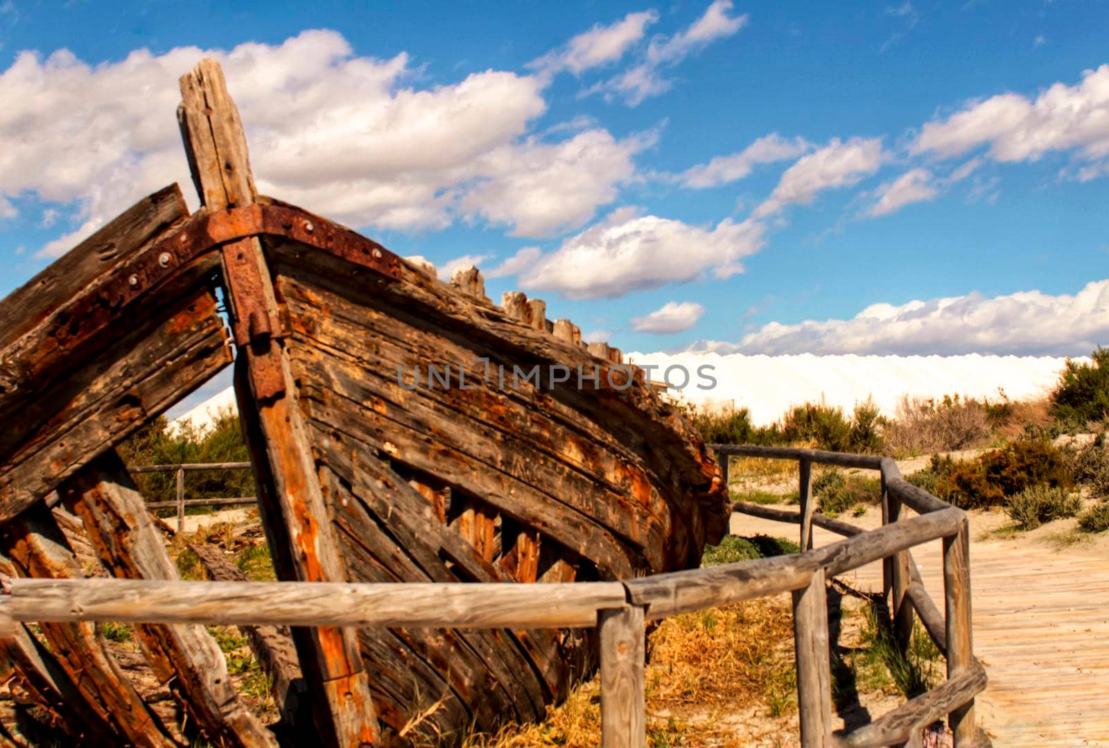 Old abandoned boat on the beach in Santa Pola. Salinas in the background under blue sky