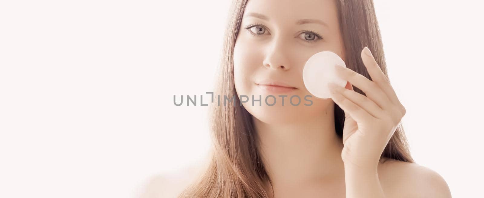 Beautiful woman with cotton pad, perfect skin and shiny hair as make-up, health and wellness concept. Face portrait of young female model for skincare cosmetics and luxury beauty ad design.