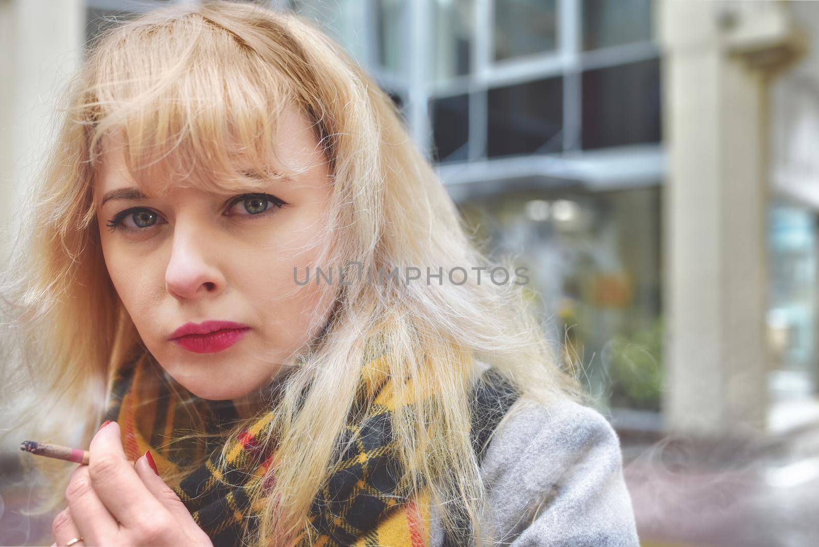 nicotine addiction Woman in a very bad mood, holding in his hand, holding a smoldering between his fingers fuming cigarette. Cigarette close-up.