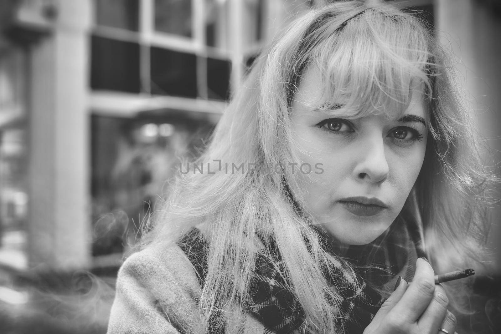 Woman in a very bad mood, holding in his hand, holding a smoldering between his fingers fuming cigarette. Cigarette close-up.