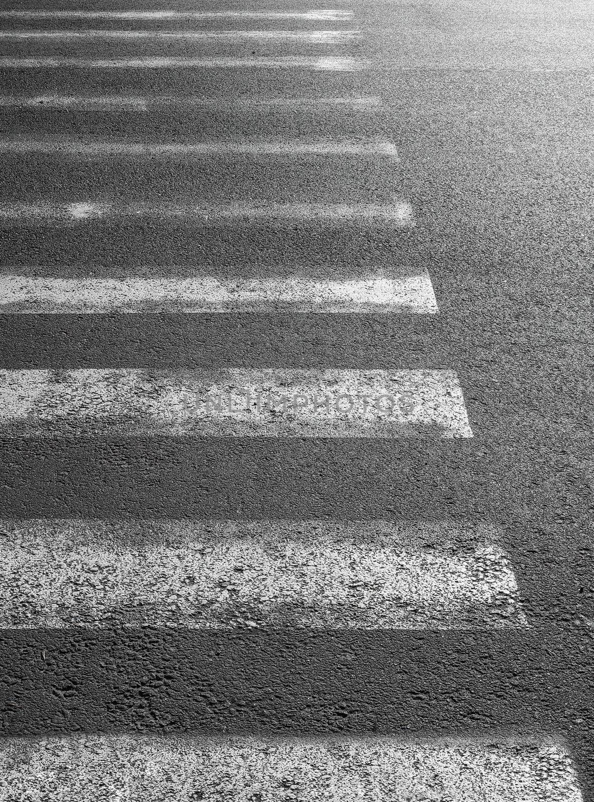 worn crosswalk on the road for safety when people walking cross the street. by Nickstock