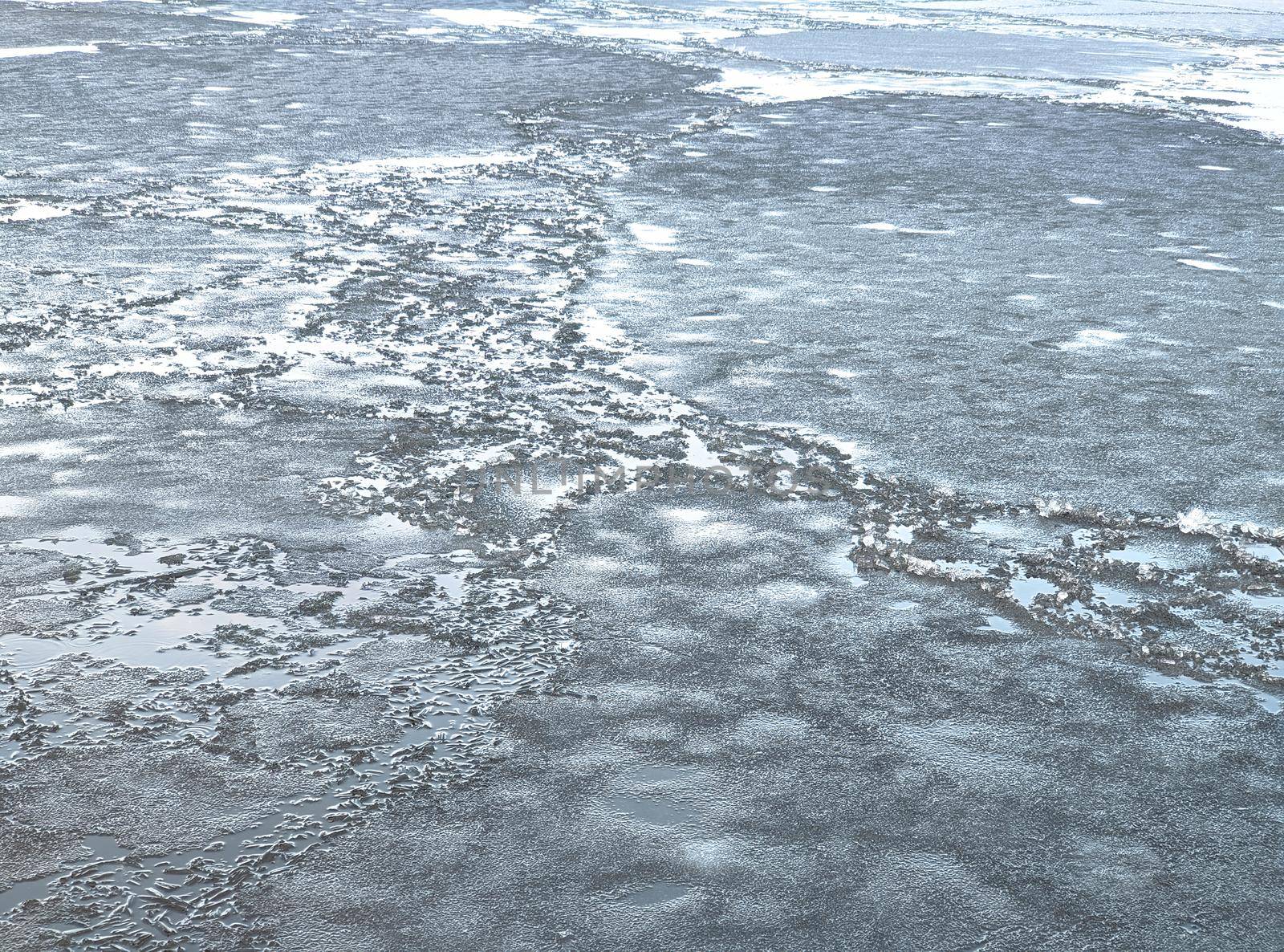 Broken ice of dark blue color on the river. Chunks of crushed ice on dark water. Abstract ice background. Blue background with cracks on the ice surface. Cracks of frozen water