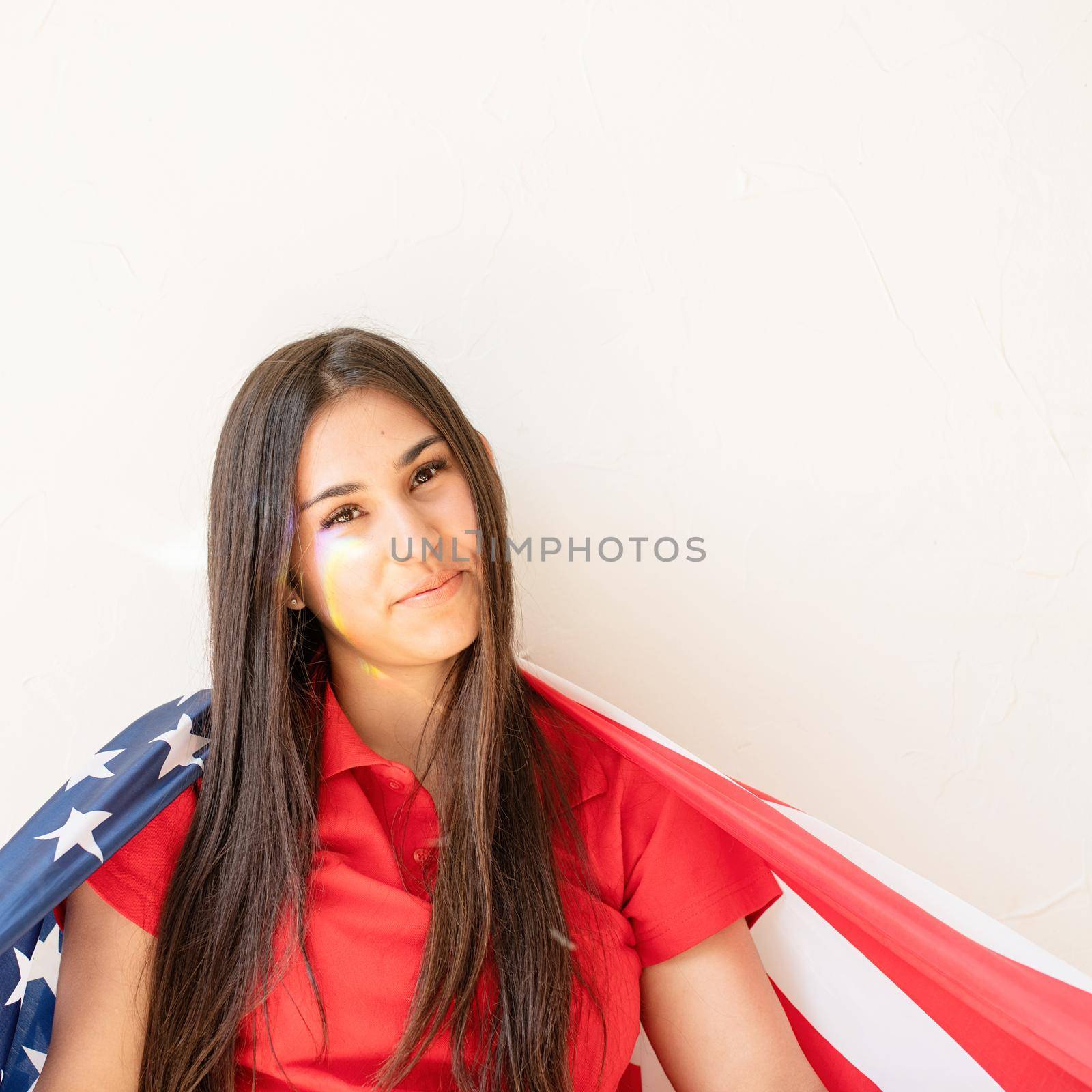 Independence day of the USA. Happy July 4th. beautiful young woman with american flag and rainbow reflection on the face. Copy space
