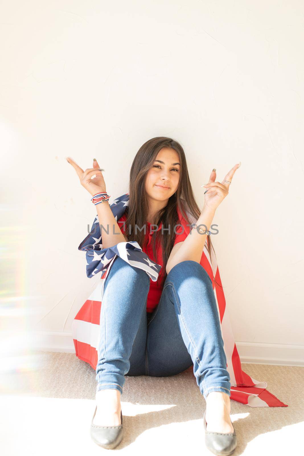 Independence day of the USA. Happy July 4th. beautiful young woman with american flag, prism rainbow reflection on the foreground. Copy space
