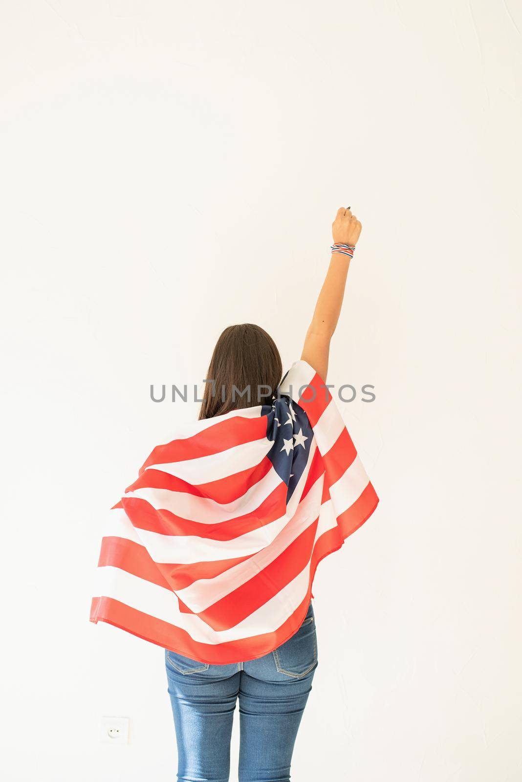 Independence day of the USA. Happy July 4th. young woman with american flag, view from behind. Copy space
