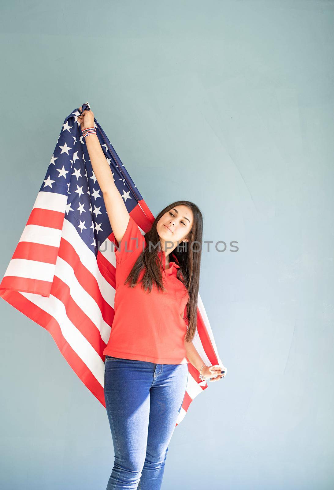 beautiful young woman with american flag on blue background by Desperada
