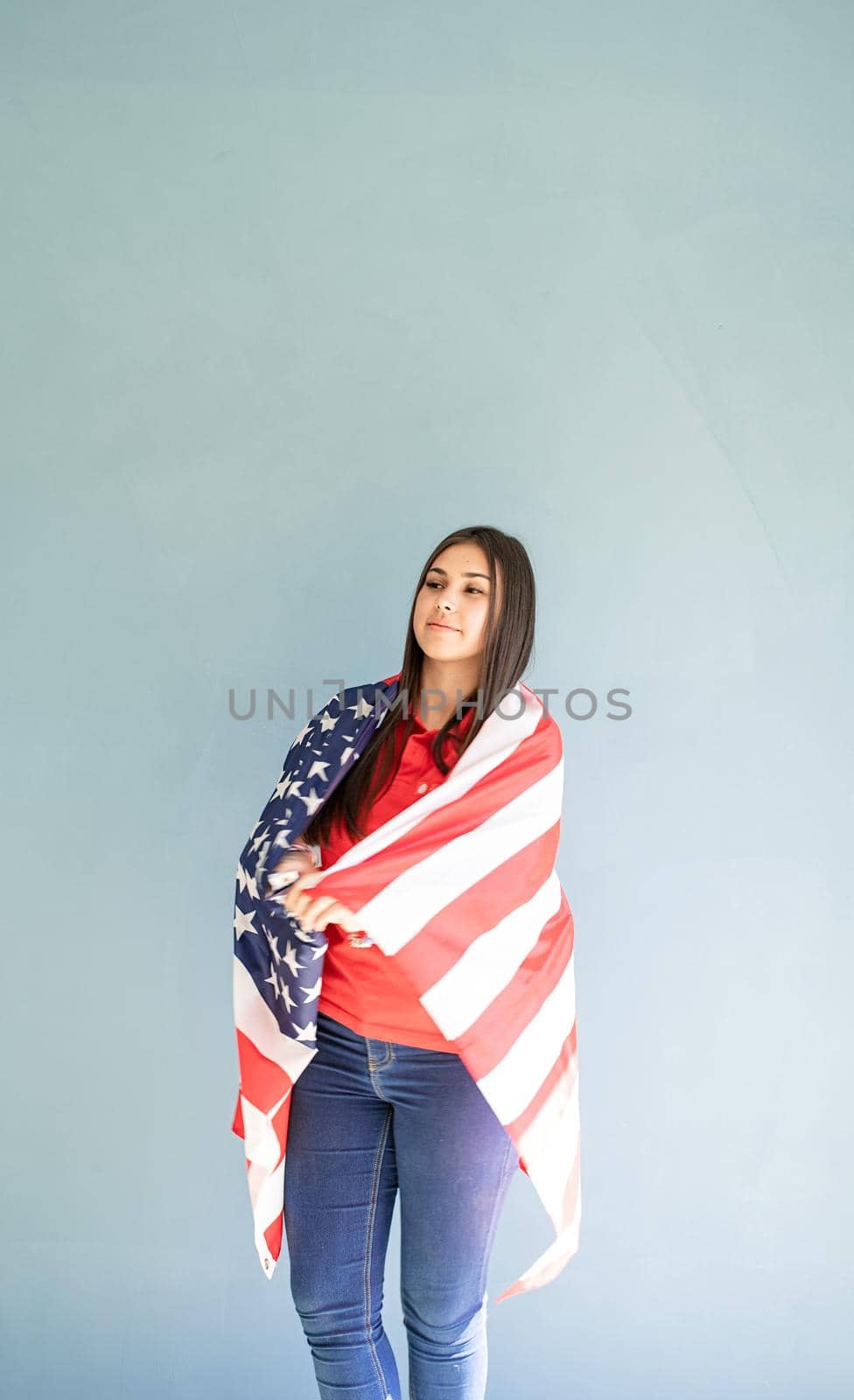 beautiful young woman wrapped in american flag on blue background by Desperada