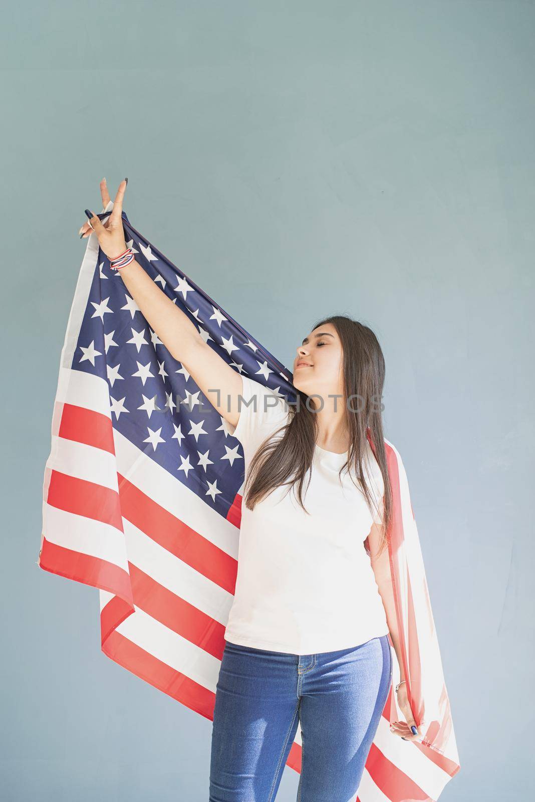 beautiful young woman with american flag on blue background by Desperada