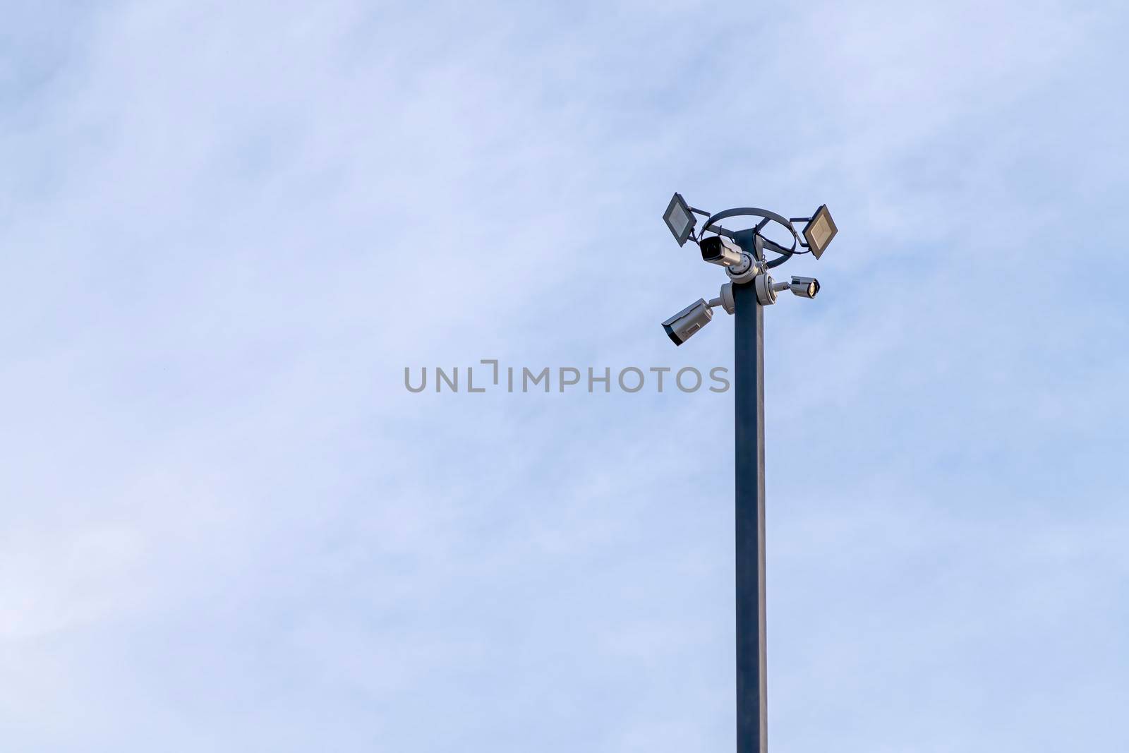 outdoor security camera on a lamppost against a blue sky by roman112007