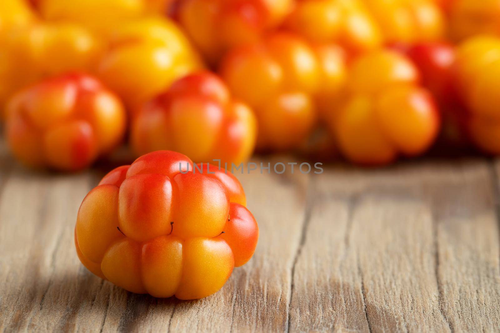 Fresh ripe cloudberries on a wooden table close-up. Selective focus.