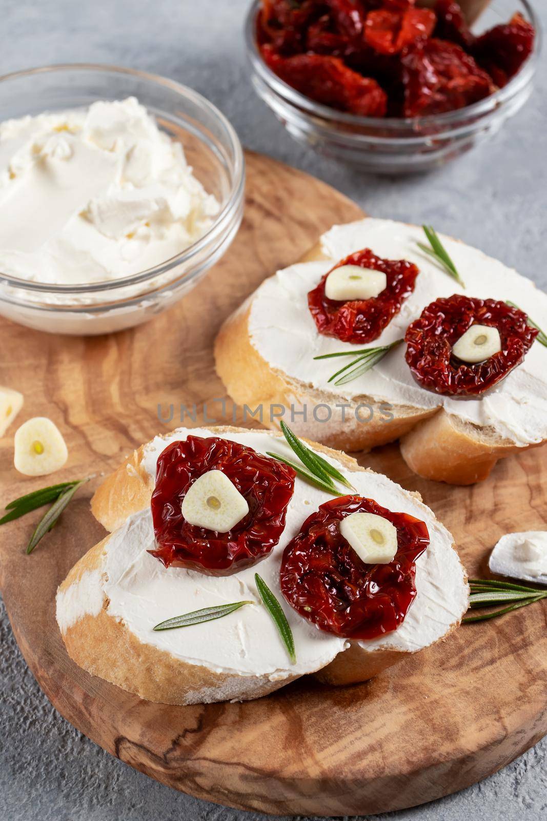 Homemade sandwiches with cream cheese and sun-dried tomatoes on a wooden board of olive - delicious healthy breakfast, italian cuisine, vertical image, copy space.