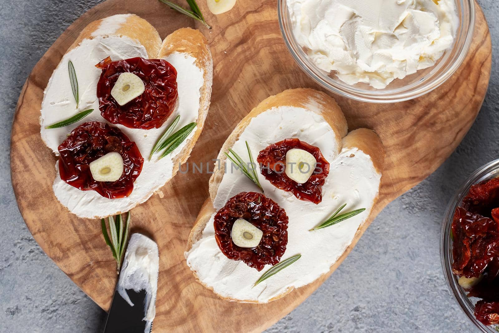 Homemade sandwiches with cream cheese and sun-dried tomatoes on a wooden board of olive - delicious healthy breakfast, italian cuisine, flat lay.