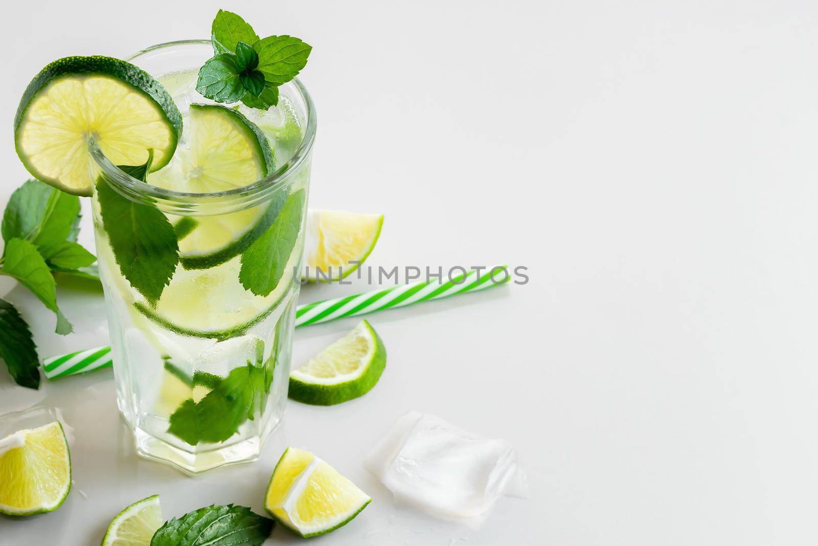 Fresh homemade cocktail with lme, mint and ice on a white table, copy space.