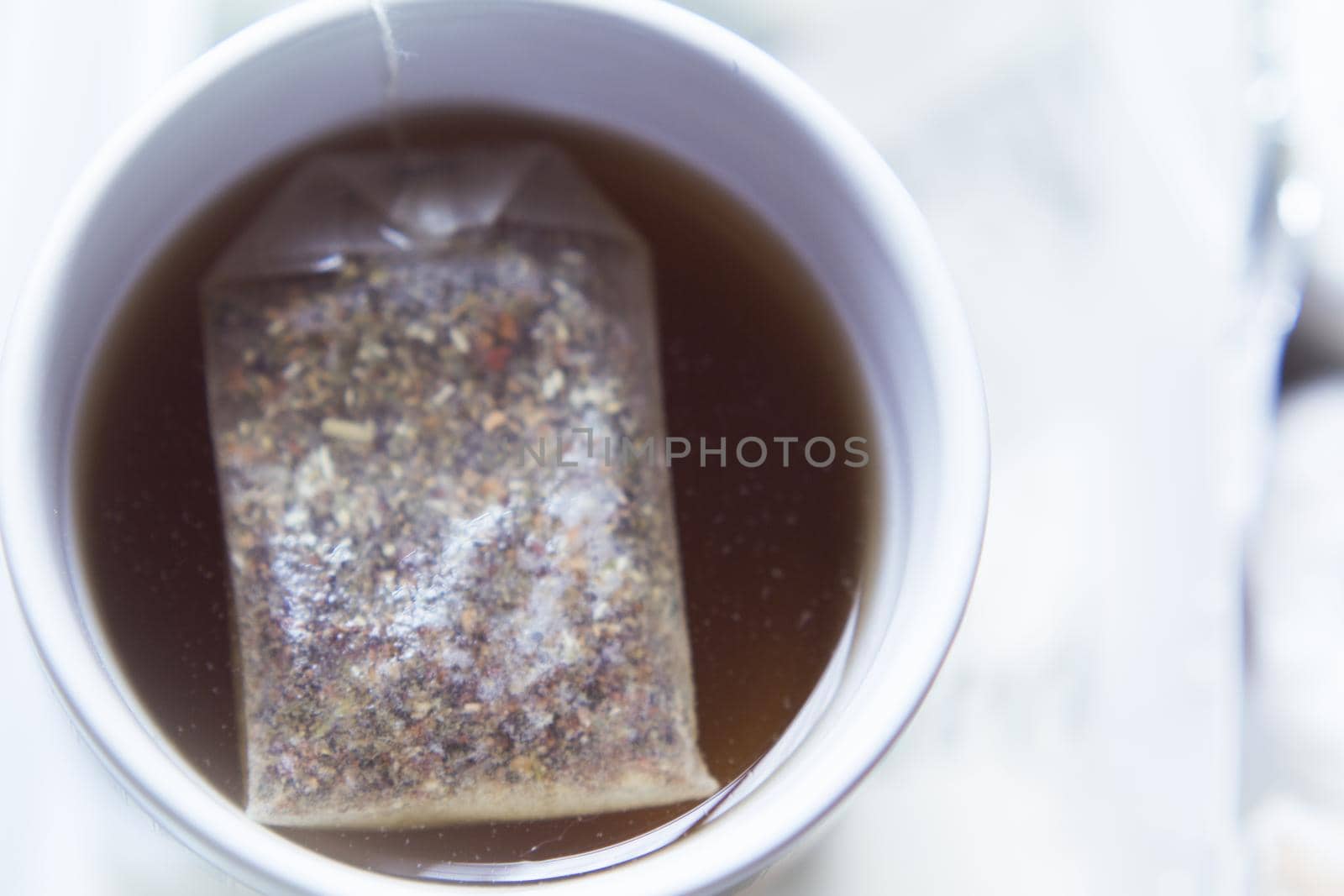 White cup with infusion and tea bag. No people