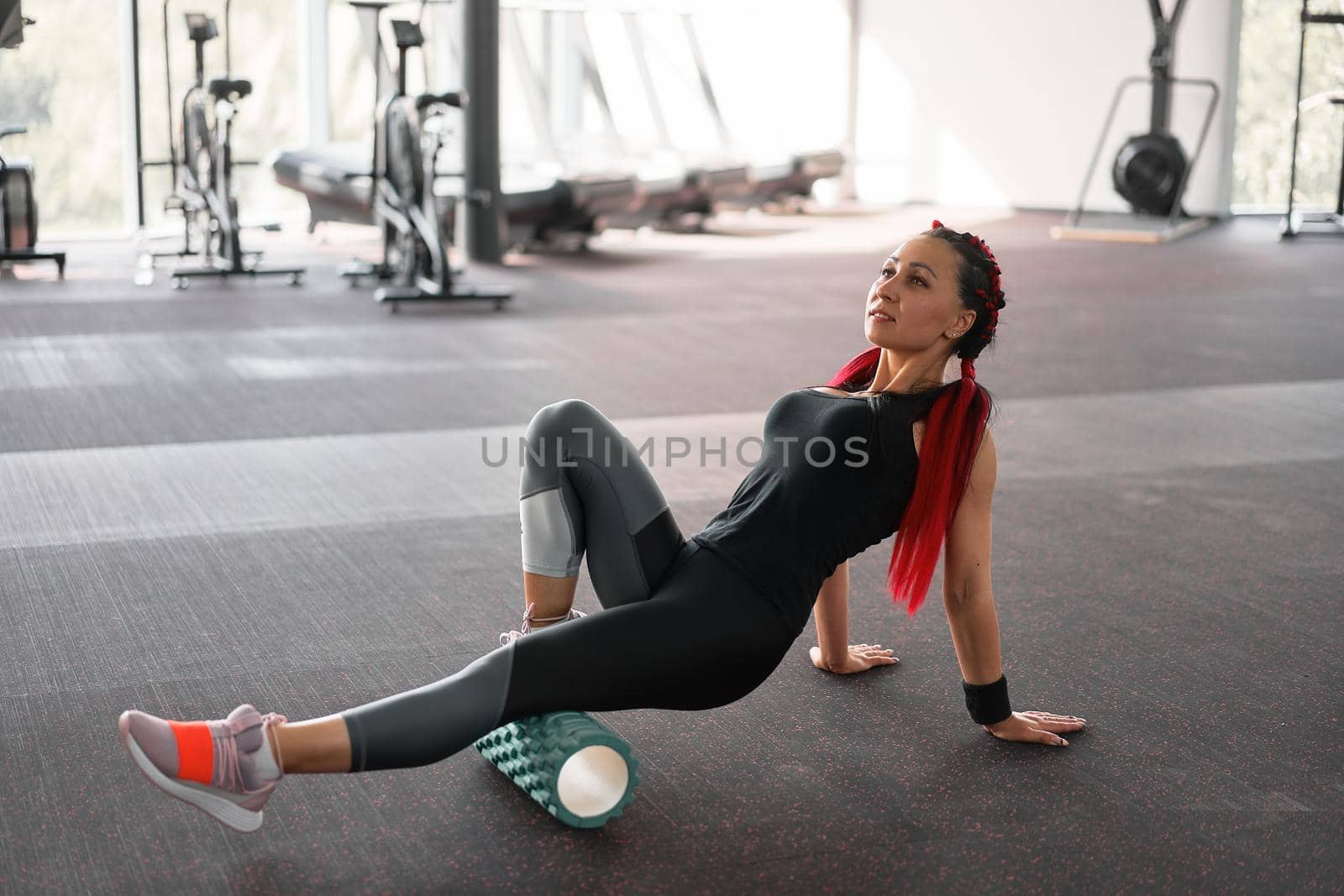 Woman massaging foam roll leg gym myofascial release exercise rolling, trigger points Middle adult caucasian woman sportswoman uses roller massager for relaxation, stretching muscles and back pain.