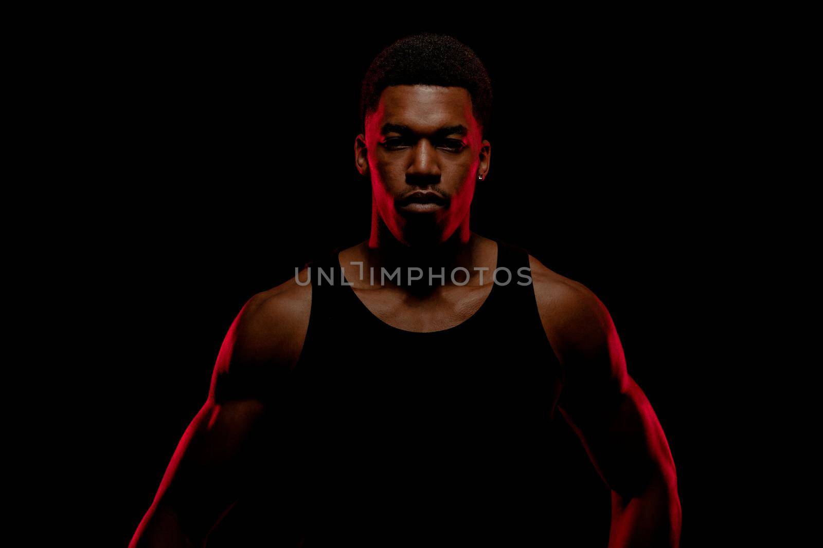 Basketball player with red side light against black background. Serious concentrated african american man. by kokimk