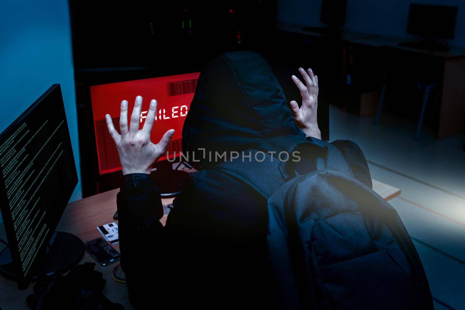 Internet criminal hacker trying to hack into corporate servers arrested by police at night. Portrait of a surrendered computer hacker who raised his hands under a flashlight. failed system hack