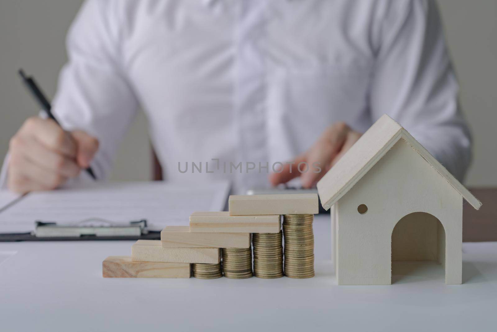 Property Taxes And Real Estate Market Growth. Property investment and house mortgage financial concept. Businessman calculating price of housing with house model, stack coin, wooden block.