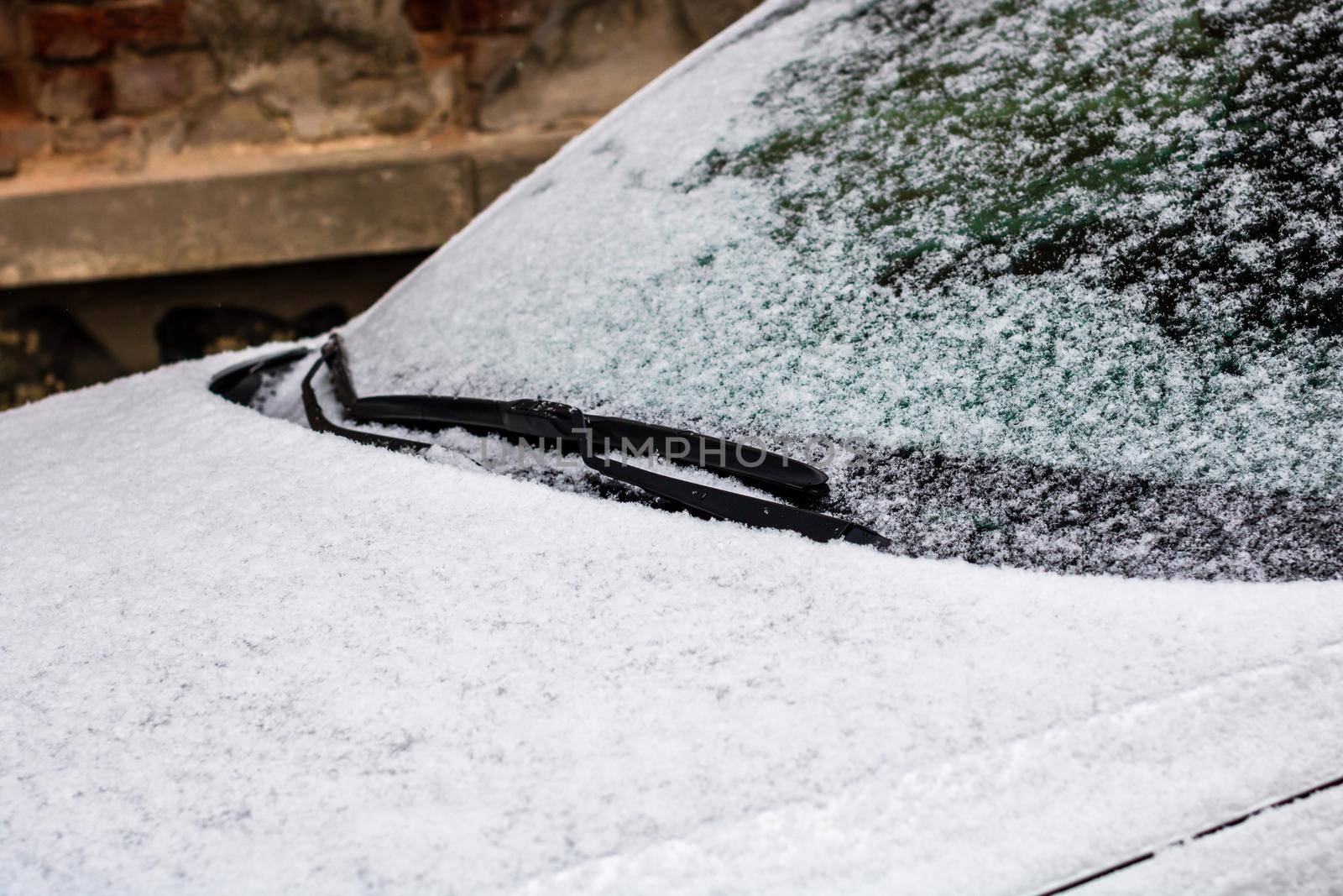 Snow on car, windshield wipers with snow close up.