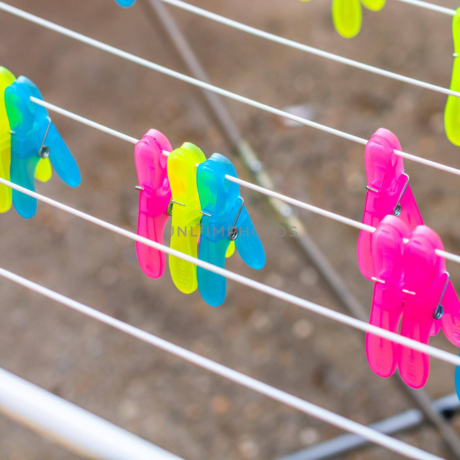 Colorful plastic clothes pegs on empty metal clothes dryer. by vladispas