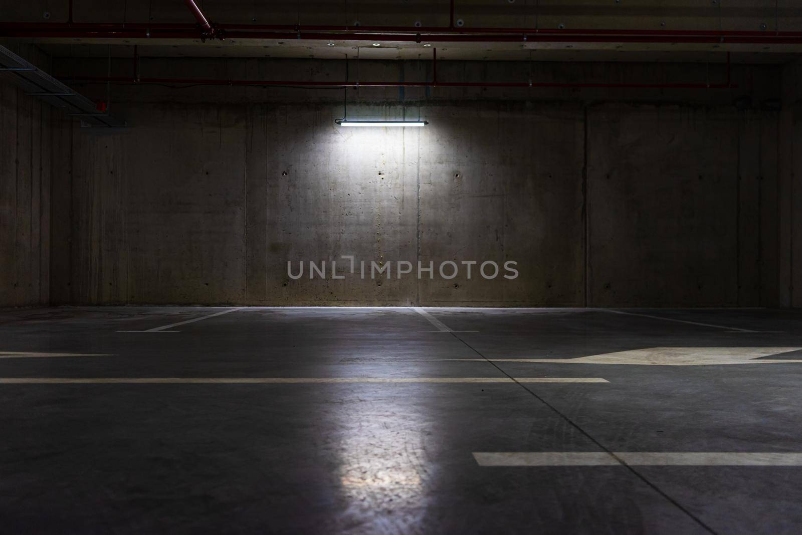 Empty parking lot with overhead dim light, underground parking garage.