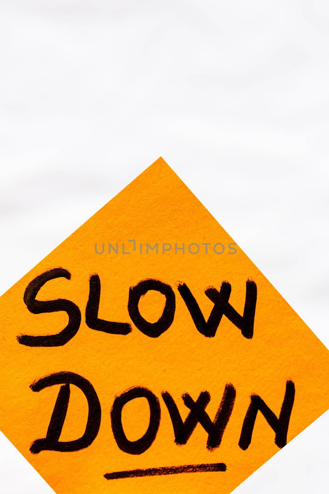 Slow down handwriting text close up isolated on yellow paper with copy space.