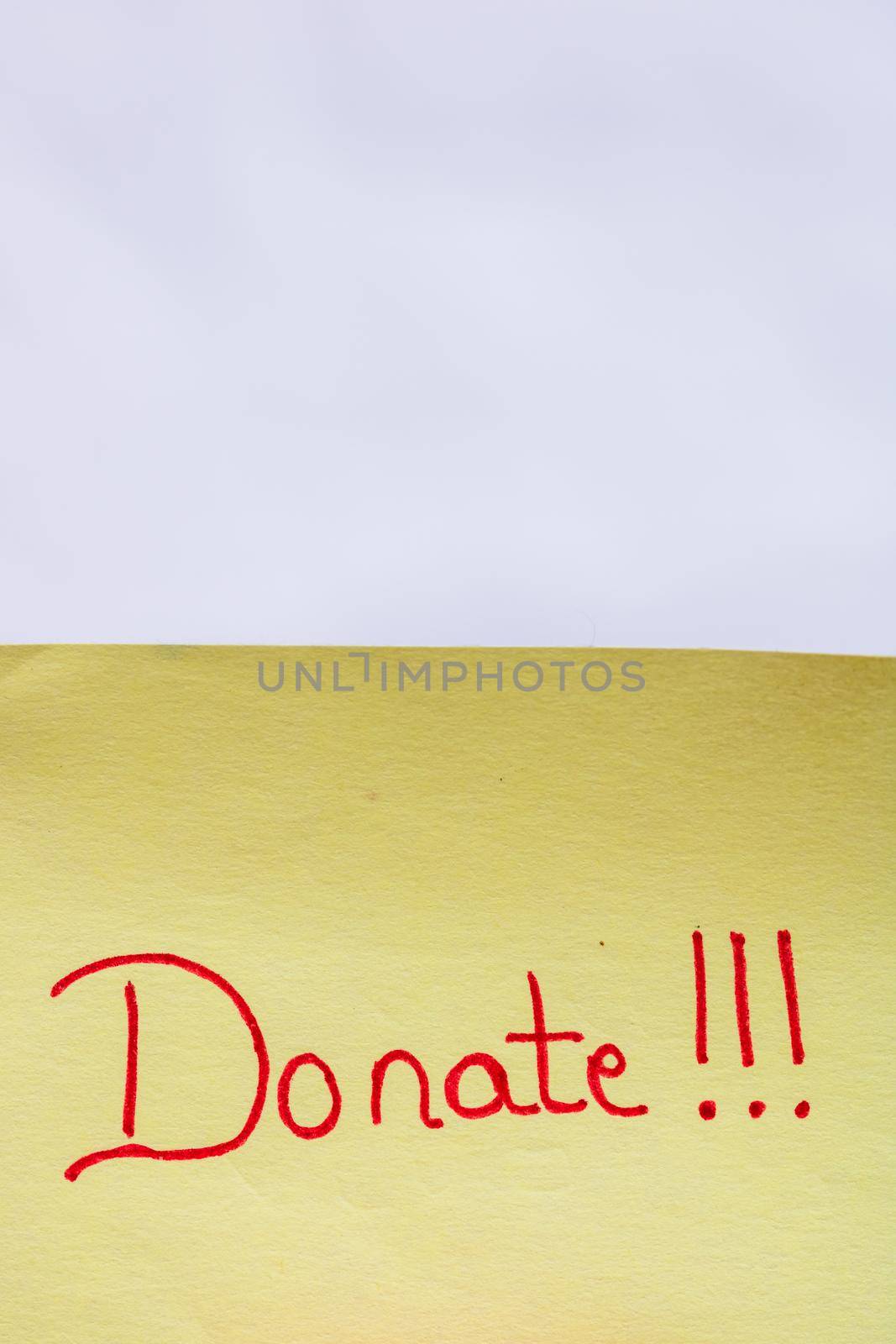  Donate handwriting text close up isolated on yellow paper with copy space. by vladispas