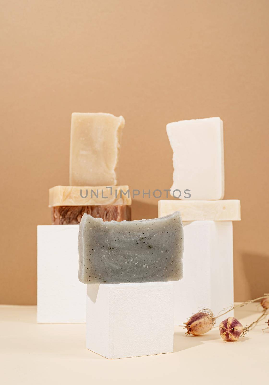 Natural organic selfcare products. Tower stack of different handmade soaps and leaves on cream background. Spa accessories creative art composition on beige background