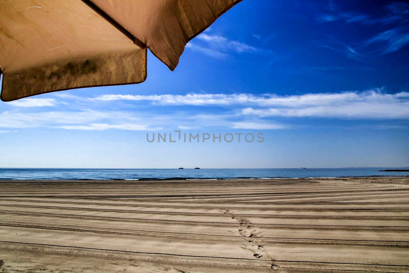 Sunny day on the beach in winter in Santa Pola, Alicante. White Umbrella in the foreground.