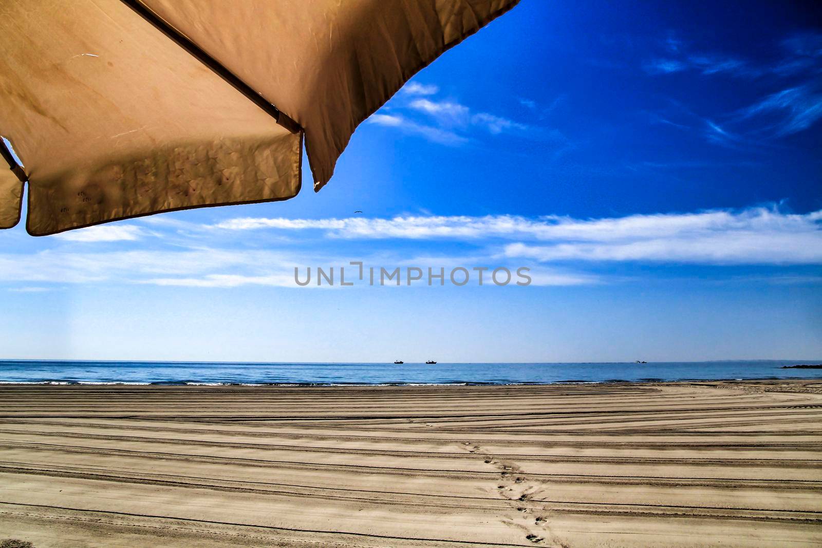 Sunny day on the beach in winter in Santa Pola, Alicante. White Umbrella in the foreground.