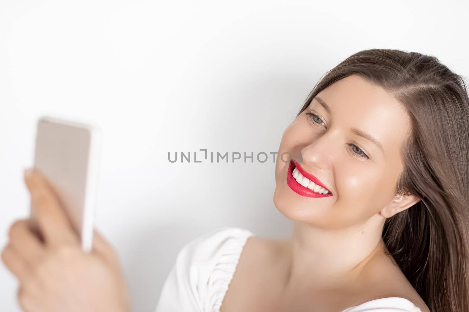 Happy smiling woman with smartphone having video call or taking selfie, portrait on white background. People, technology and communication concept.