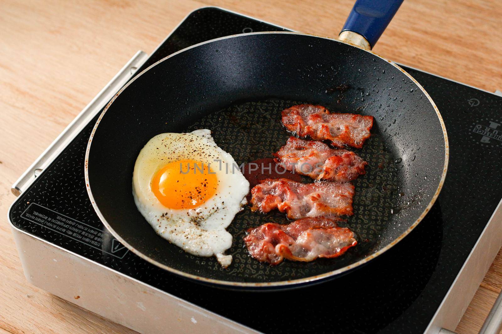 Tasty breakfast with fried eggs and bacon in a pan by uphotopia