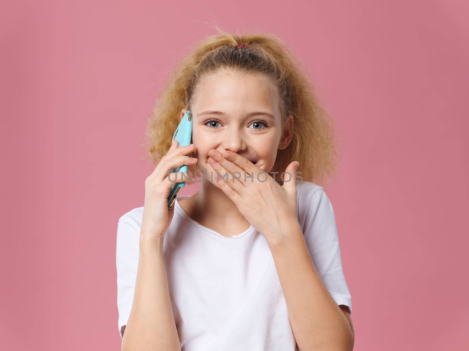 Girl talking on the phone well secret white t-shirt pink isolated background smile