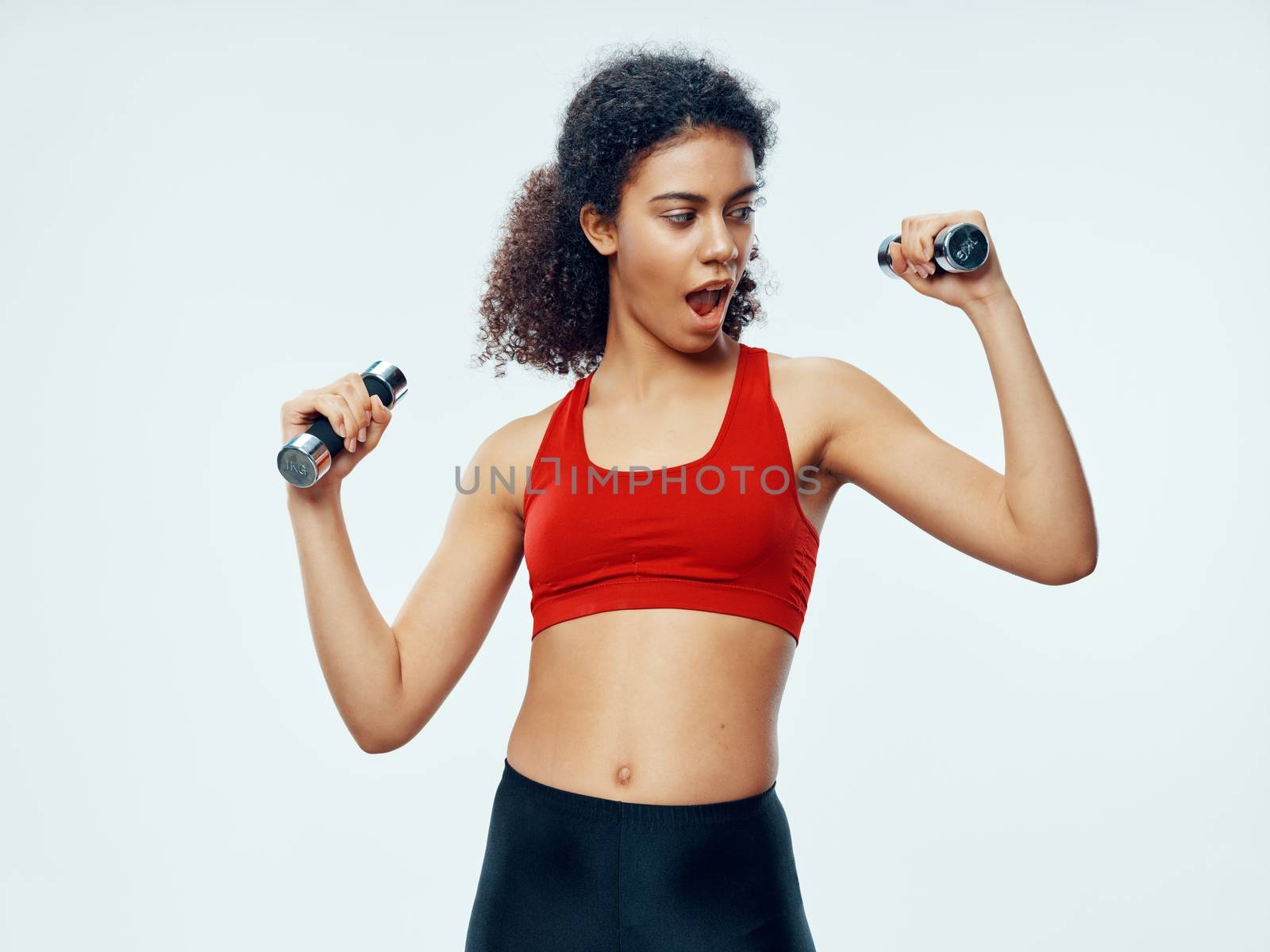 sporty woman with dumbbells on isolated background leggings and red tank top