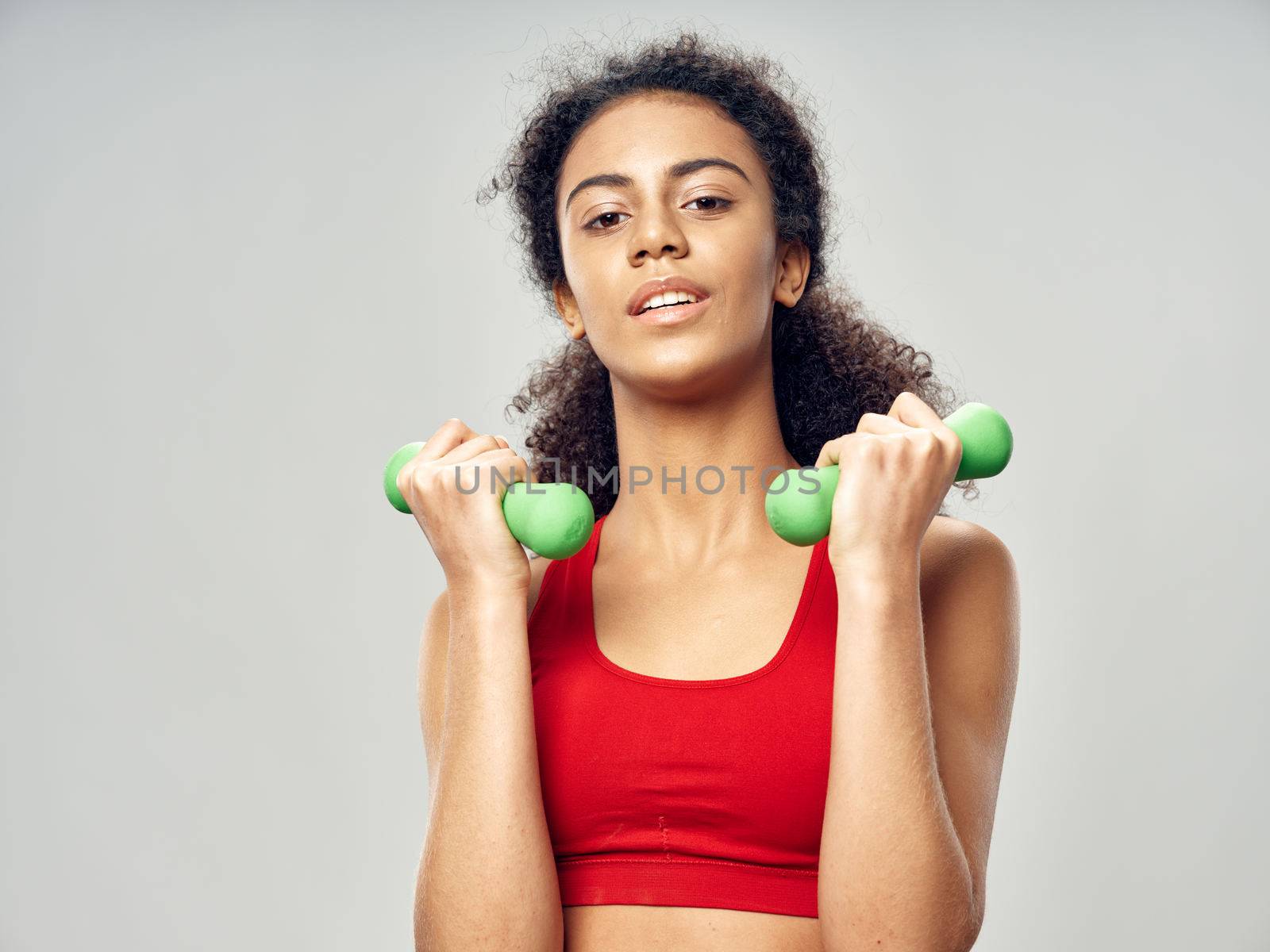 green dumbbells in the hands of a slender woman who plays sports