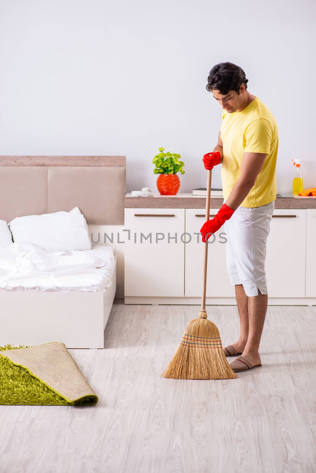 Young handsome man cleaning in the bedroom