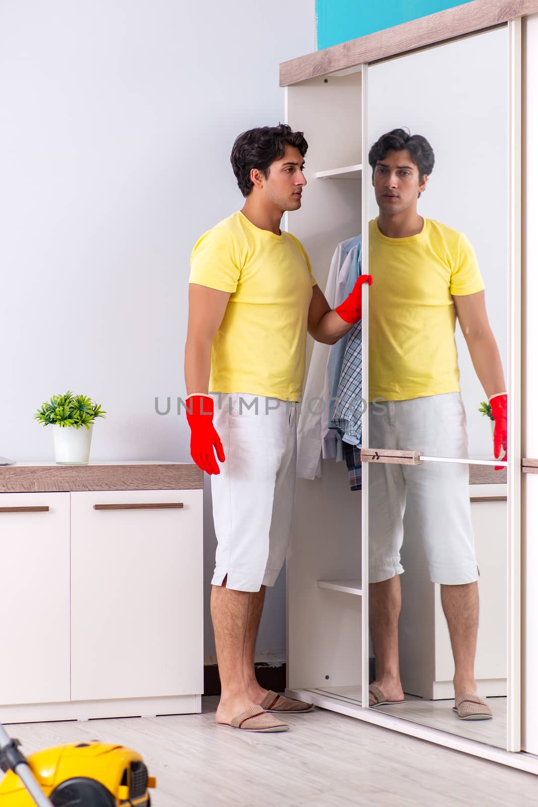 Young handsome man cleaning in the bedroom
