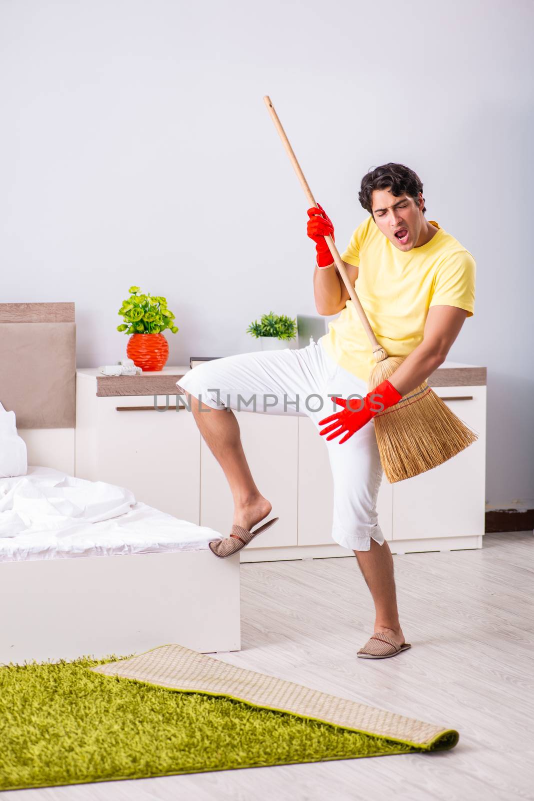 Young handsome man cleaning in the bedroom