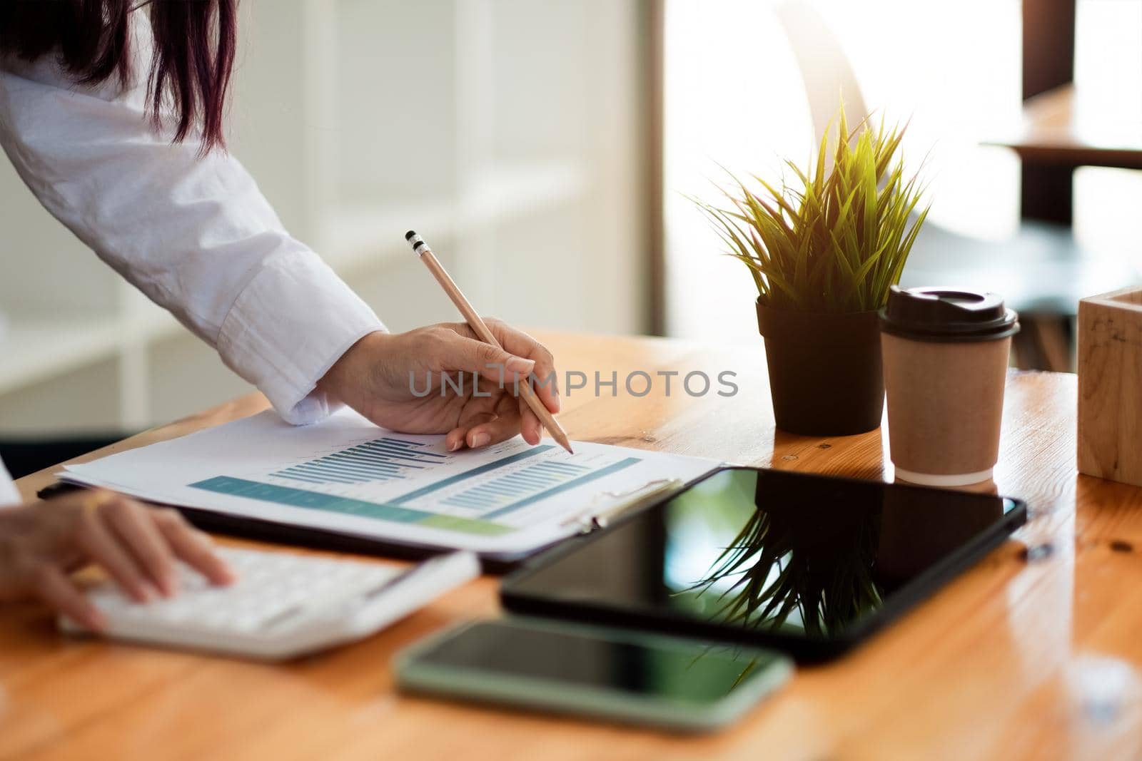 Businesswoman inspecting and checking the business reports graphs to audit the financial reports by calculating the results. Analyzing the revenue and auditing the budget concept by nateemee