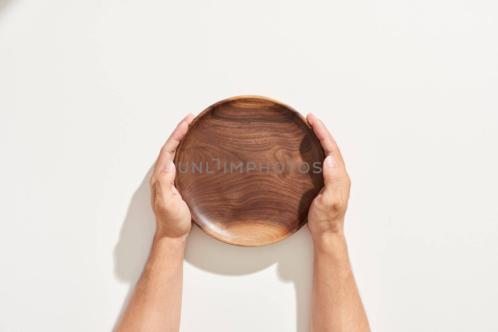 hand holding Empty wooden plate isolated on white background