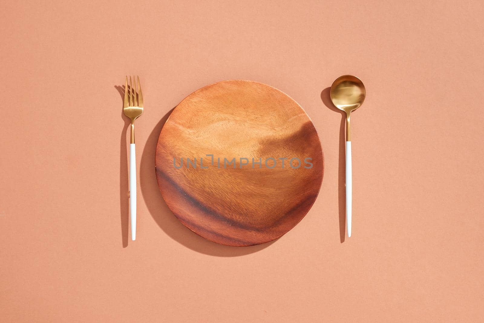 Knife and fork on wooden plate isolated on beige background with copy space  by makidotvn